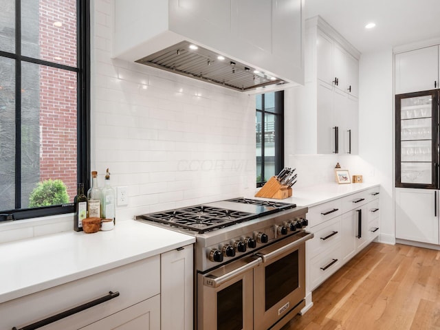 597 S 9th St, Columbus, OH 43206 - kitchen featuring range with two ovens, wall chimney exhaust hood, healthy amount of natural light, white cabinetry, and recessed lighting