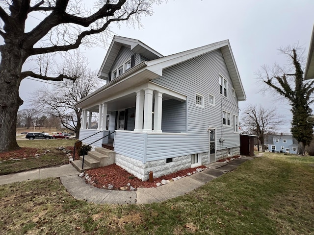 view of side of home with covered porch and a yard