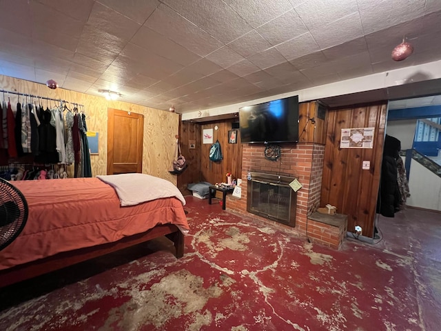 carpeted bedroom featuring a brick fireplace and wood walls