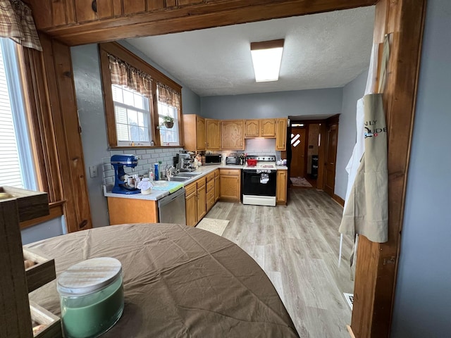 kitchen with electric stove, tasteful backsplash, light countertops, light wood-type flooring, and dishwasher