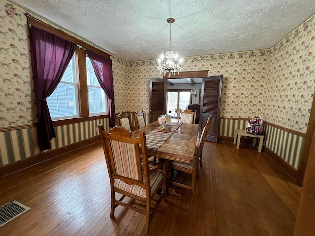 dining area featuring a textured ceiling, hardwood / wood-style floors, and wallpapered walls