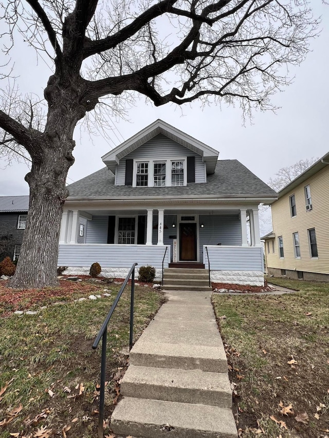 bungalow-style house featuring a porch and roof with shingles