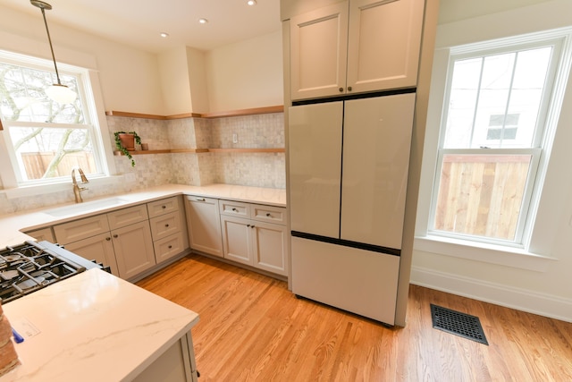 kitchen featuring visible vents, white fridge, light wood-type flooring, open shelves, and a sink