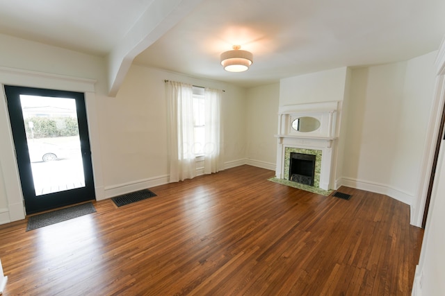 unfurnished living room with baseboards, visible vents, wood finished floors, and a tile fireplace