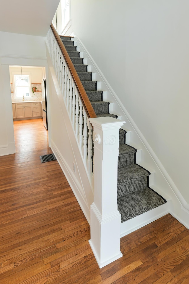 stairs featuring wood-type flooring, visible vents, and baseboards