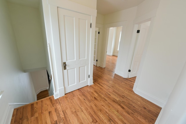 hall featuring light wood-type flooring and baseboards