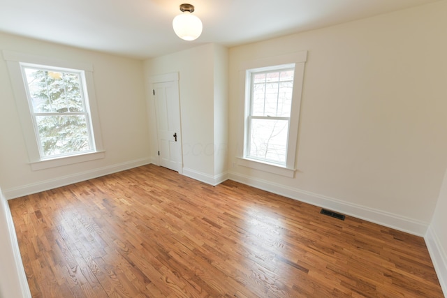 empty room featuring light wood-type flooring, visible vents, and baseboards