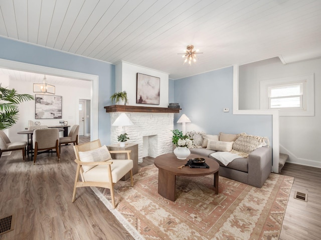 living room featuring a notable chandelier, a fireplace, wood ceiling, visible vents, and light wood-style floors