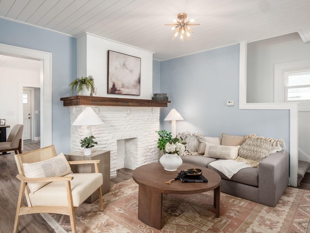 living room with light wood-type flooring, wooden ceiling, and a stone fireplace