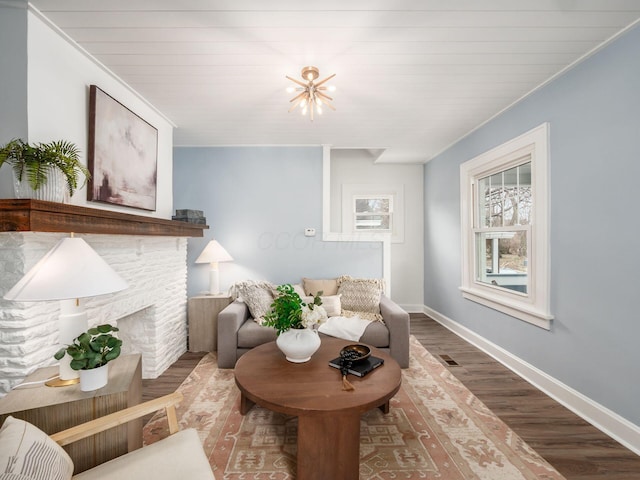 living area featuring a fireplace, wood finished floors, an inviting chandelier, and baseboards