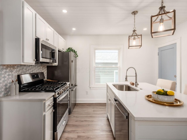 kitchen with stainless steel appliances, backsplash, a sink, an island with sink, and light wood-type flooring