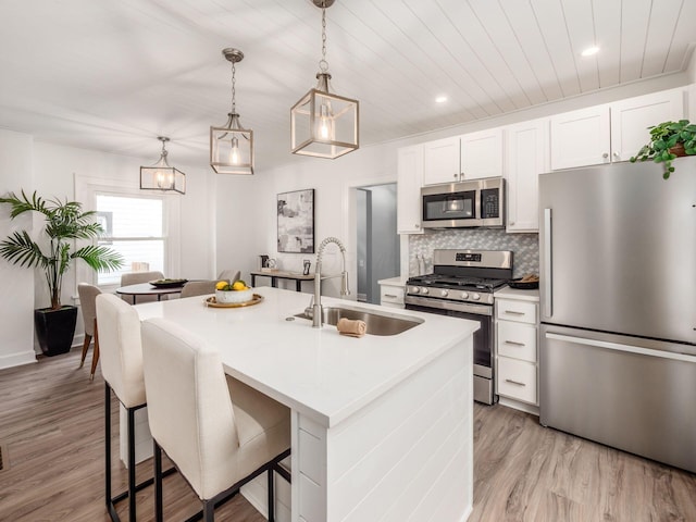 kitchen featuring appliances with stainless steel finishes, a sink, light countertops, white cabinetry, and backsplash