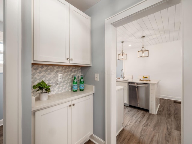 bar with light wood-style flooring, a sink, baseboards, dishwasher, and tasteful backsplash