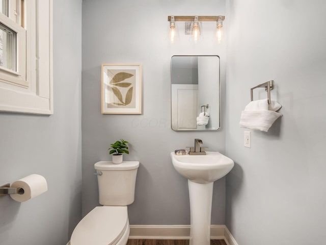 half bathroom with baseboards and toilet