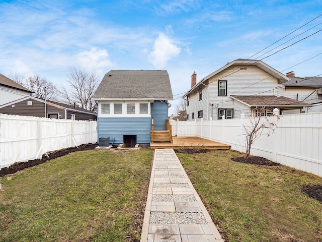 rear view of house featuring a fenced backyard, roof with shingles, a yard, a wooden deck, and central air condition unit