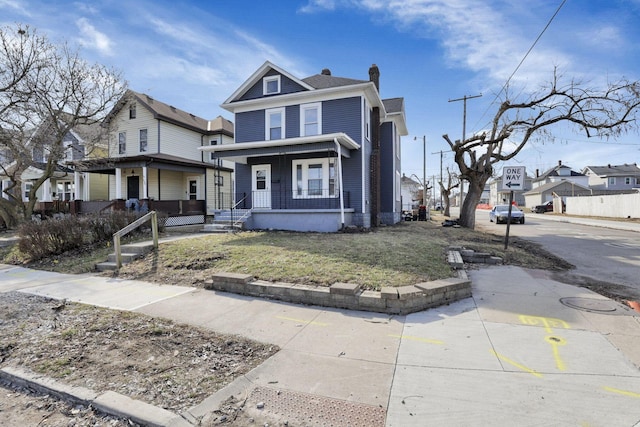 american foursquare style home featuring a porch, a residential view, and a front yard