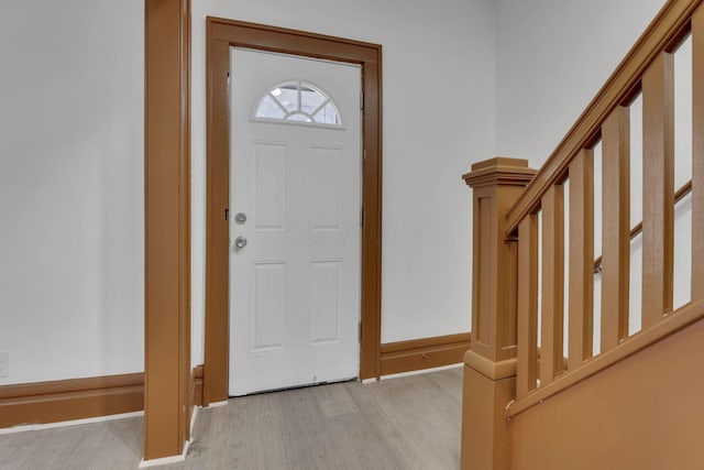 entrance foyer with light wood-style floors, baseboards, and stairway