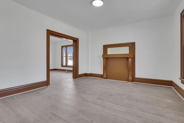 unfurnished room with light wood-type flooring and baseboards