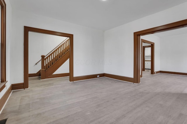 spare room featuring light wood-style floors, visible vents, baseboards, and stairs