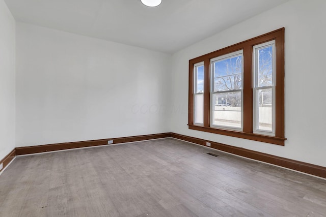 empty room featuring visible vents, baseboards, and wood finished floors