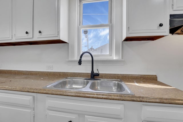 kitchen with dark countertops, white cabinets, and a sink