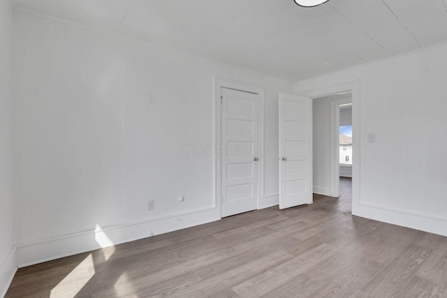 spare room with ornamental molding and wood finished floors