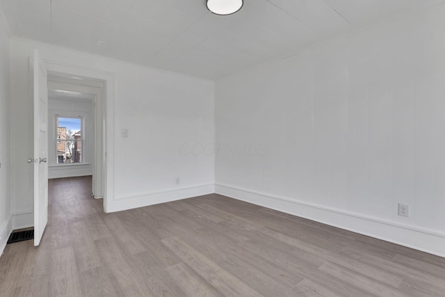 spare room with baseboards and wood finished floors