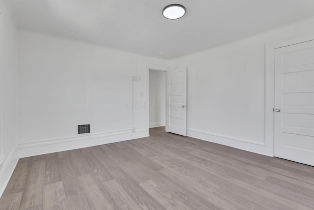 empty room with visible vents, baseboards, and wood finished floors