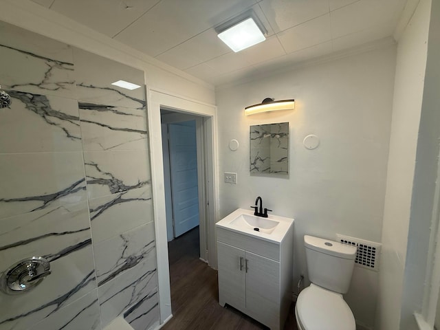 bathroom with toilet, wood finished floors, visible vents, vanity, and ornamental molding