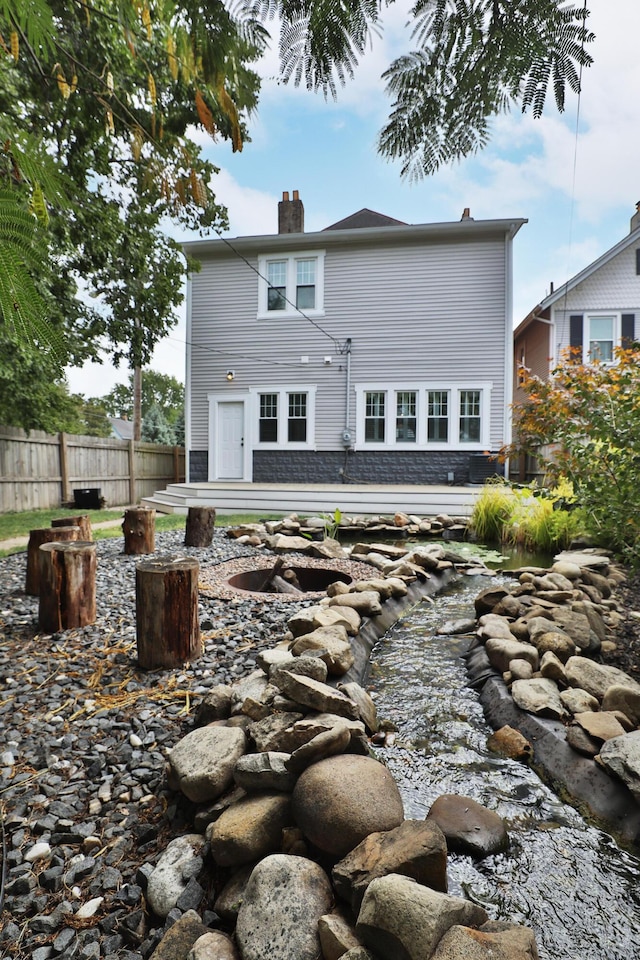 back of house featuring a chimney and fence