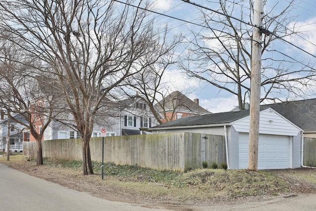 view of side of home with a garage, fence, and an outdoor structure