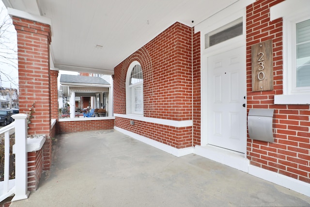 property entrance with brick siding and a porch