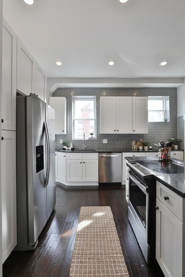 kitchen with dark wood-style flooring, backsplash, appliances with stainless steel finishes, a healthy amount of sunlight, and a sink