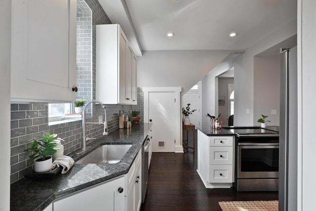 kitchen featuring stainless steel appliances, decorative backsplash, dark wood-type flooring, white cabinets, and a sink