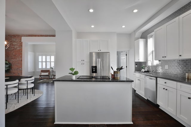 kitchen with appliances with stainless steel finishes, dark wood-style flooring, white cabinets, and a center island