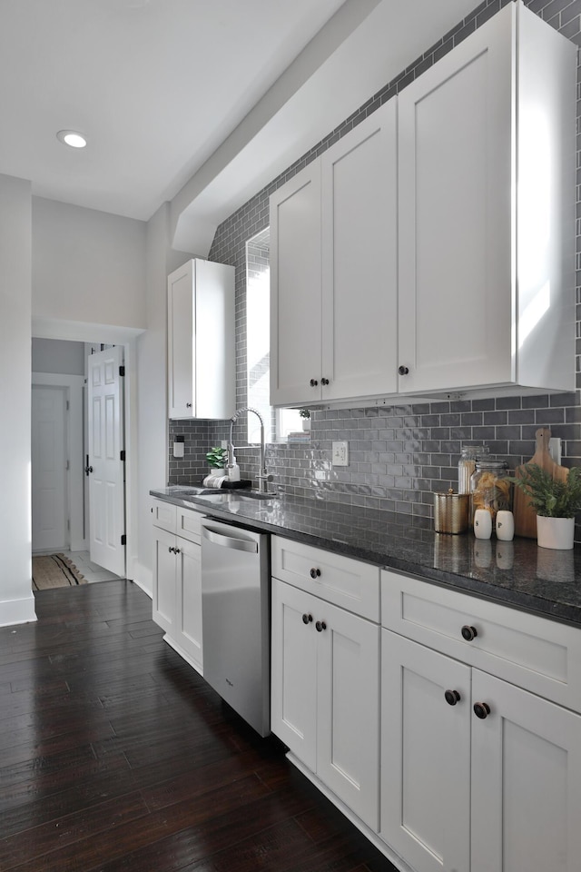 kitchen featuring white cabinets, backsplash, dark wood-type flooring, and stainless steel dishwasher