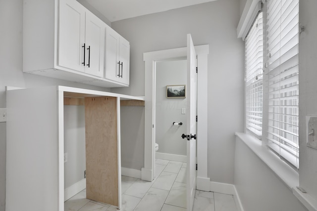 washroom with marble finish floor and baseboards