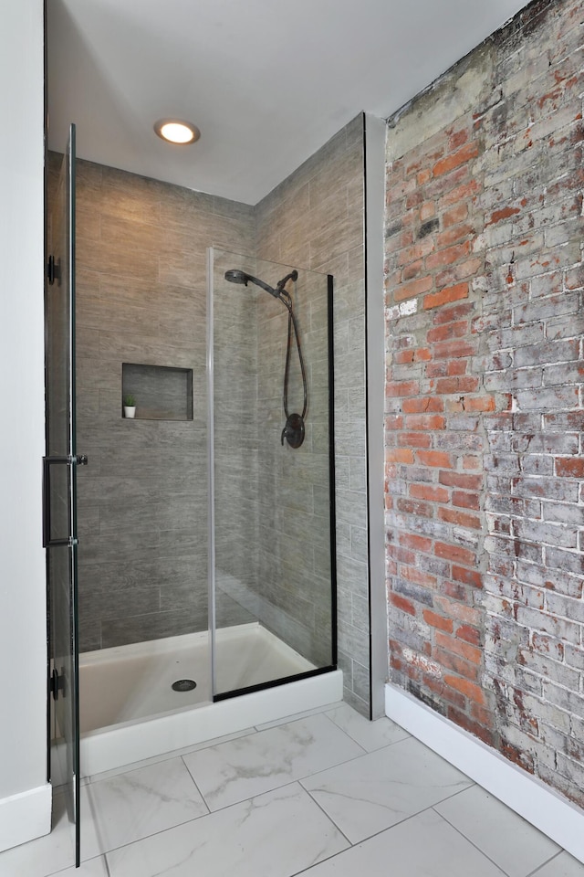 full bathroom featuring marble finish floor, a shower stall, and baseboards