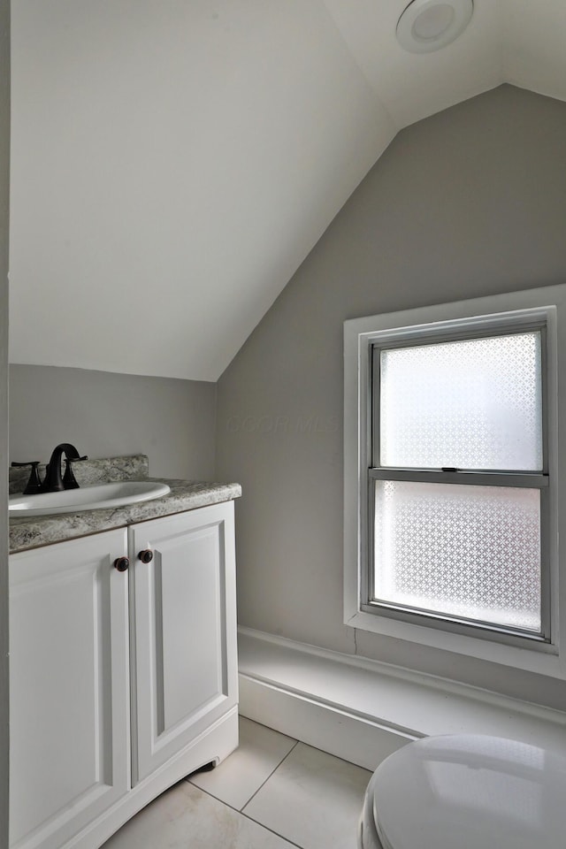 half bath with toilet, tile patterned floors, vaulted ceiling, and vanity