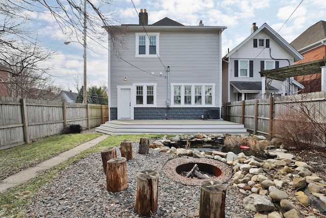 rear view of house with a deck, an outdoor fire pit, central AC unit, a fenced backyard, and a chimney