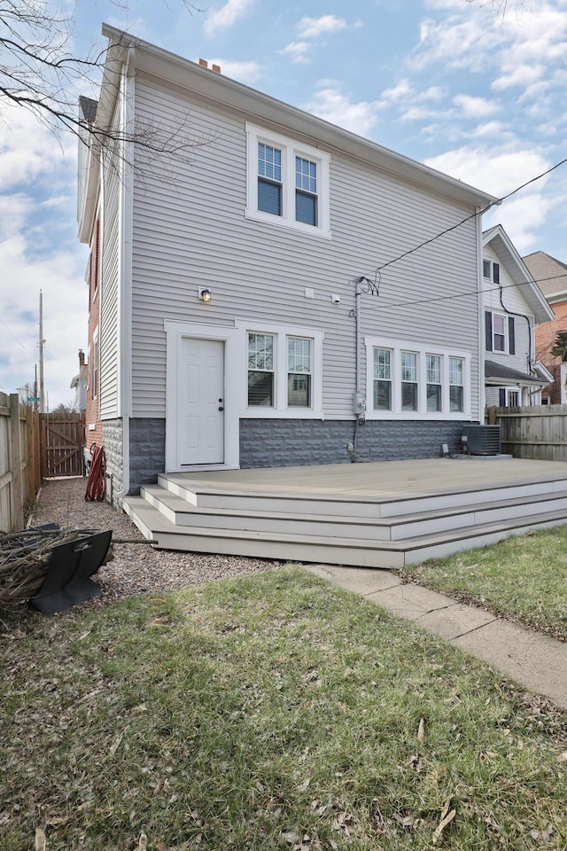 back of property featuring fence, a lawn, a wooden deck, and central AC unit