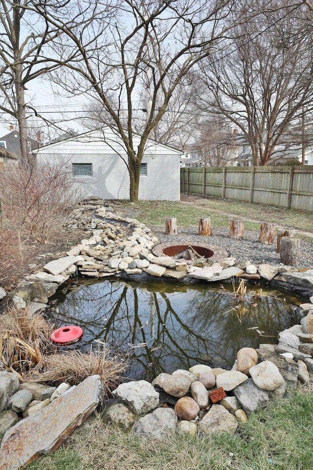 view of yard with fence and a garden pond