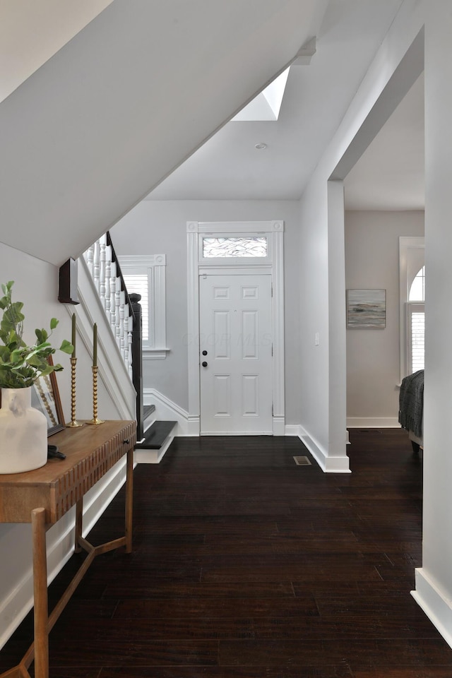 foyer featuring stairs, a skylight, baseboards, and wood finished floors