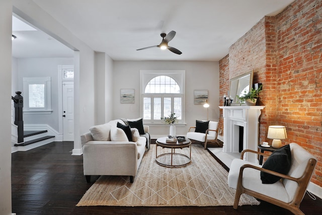 living room featuring wood-type flooring, baseboards, a fireplace with raised hearth, and a ceiling fan