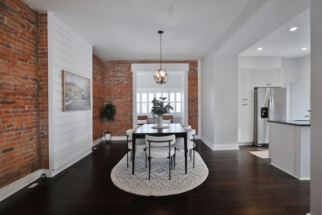 dining space featuring dark wood-style floors, recessed lighting, baseboards, and brick wall