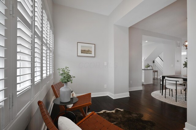 living area with dark wood-style floors, stairs, and baseboards