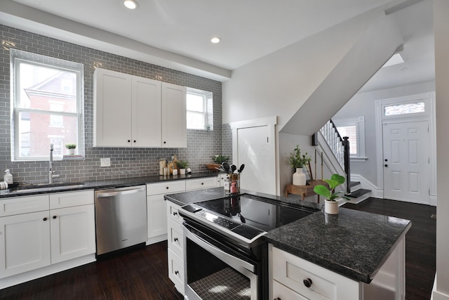 kitchen featuring stainless steel appliances, a sink, white cabinets, decorative backsplash, and dark wood finished floors