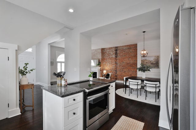 kitchen with stainless steel appliances, dark wood-type flooring, a fireplace, and white cabinets