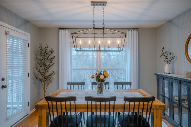 dining space featuring light wood-type flooring, baseboards, and a notable chandelier