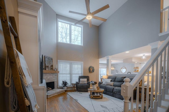 living room with stairway, plenty of natural light, a fireplace, and wood finished floors